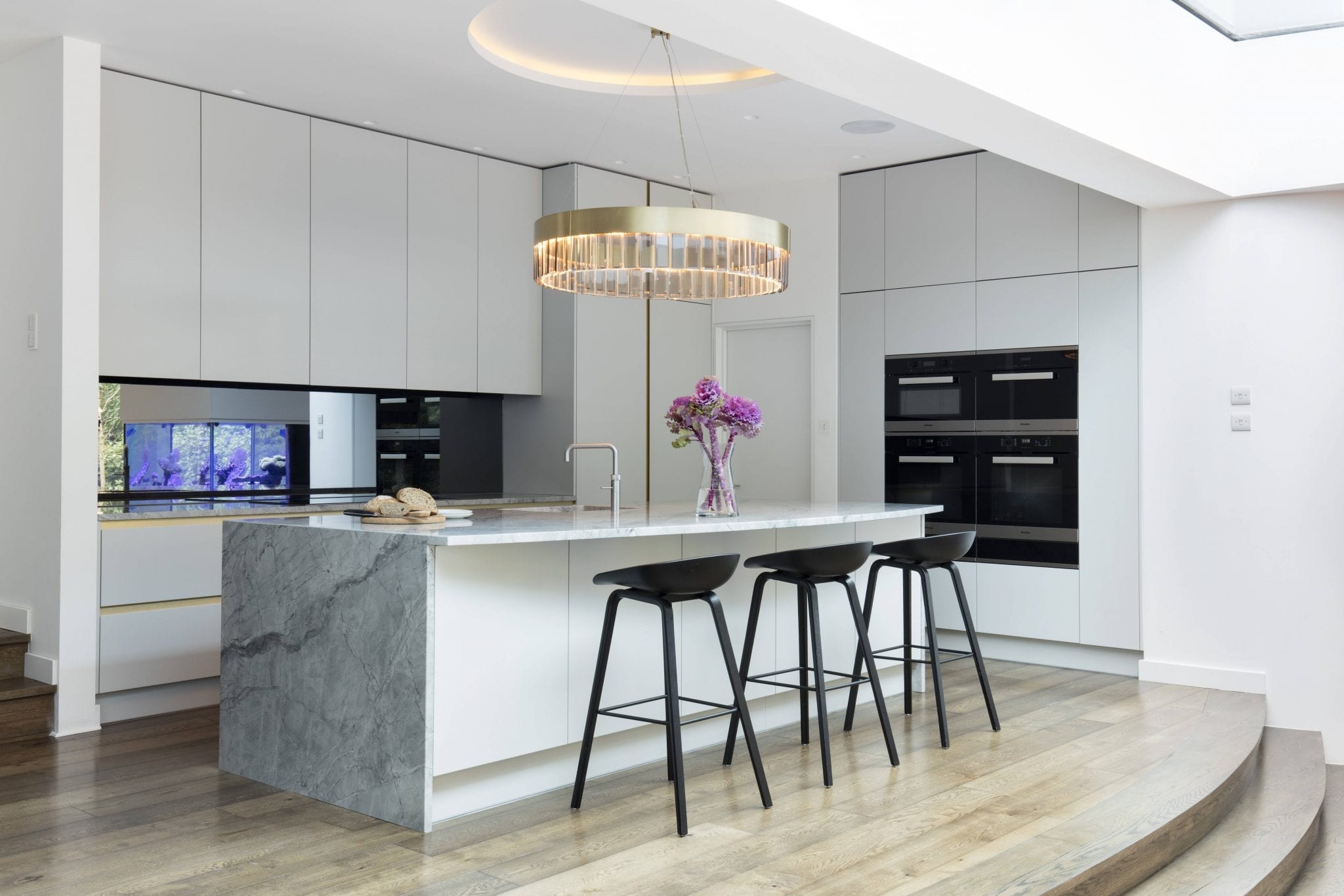 A London kitchen renovated by Amberth, featuring a kitchen island in Moonrock granite and handleless cabinets.